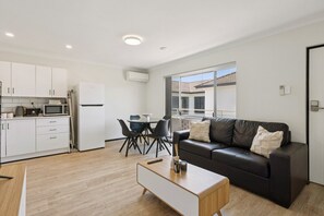 A modern apartment with a kitchen, dining area, and living room. - Charming Riverside Foreshore (South Perth)