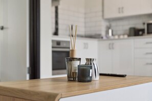 A kitchen counter with a bottle of vanilla absolute, a glass candle, and a vase. - Charming Riverside Foreshore (South Perth)