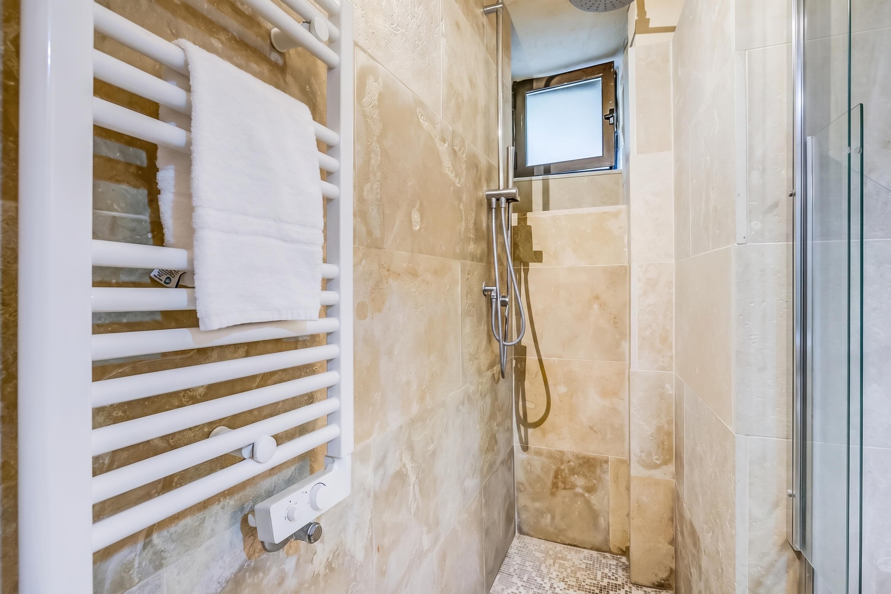 A bathroom with a shower, a towel rack, and a small mirror.