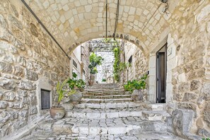 A stone staircase leading to an arched doorway in a narrow alleyway with potted plants. - Borgo Hedone - Jasmine, Scicli, Italy (Scicli)