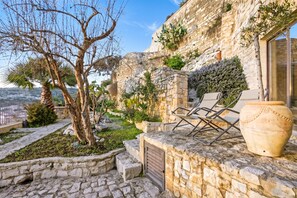 A stone building with a garden, a large vase, and a chair. - Borgo Hedone - Jardin, Scicli, Italy (Scicli)
