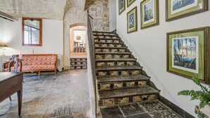 Un escalier aux marches richement décorées, un canapé, une table et des tableaux encadrés accrochés aux murs.