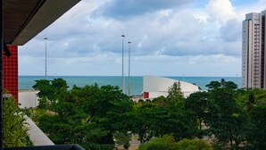 Vista de una zona costera con un edificio moderno, árboles y cielo despejado.