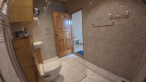 A bathroom with a toilet, sink, and shower area.