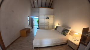 A bedroom with a bed, bedside tables, a bench, a wardrobe, and a view of the outdoors.