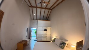 A bedroom with a bed, bedside table, lamp, and a view of the outside.