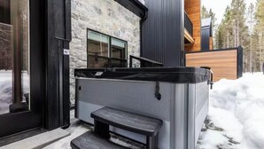 Un jacuzzi al aire libre frente a un edificio de fachada de piedra y terraza de madera.