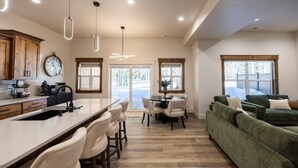 Cocina moderna con una isla central, comedor con sillas y un sofá verde.