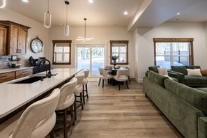 Eine moderne Küche mit Kochinsel, Essbereich mit Stühlen und einem grünen Sofa.