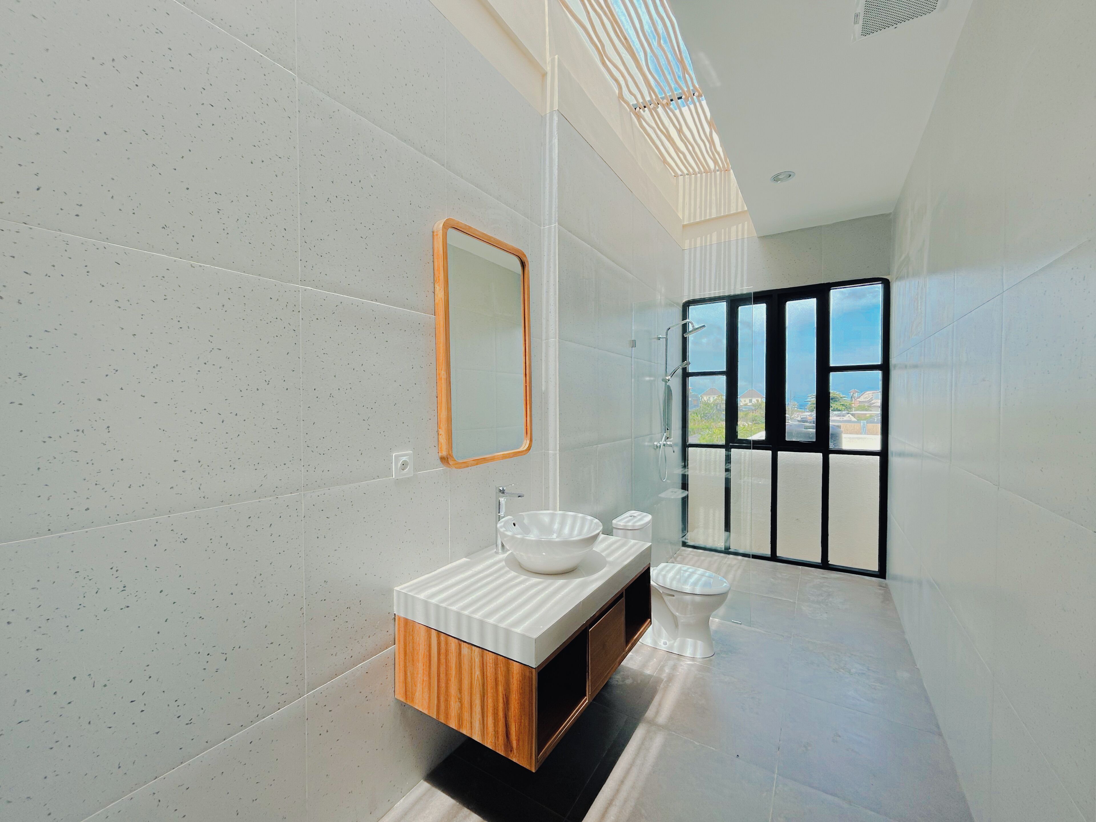 A modern bathroom with a large mirror, a vessel sink, and a toilet.