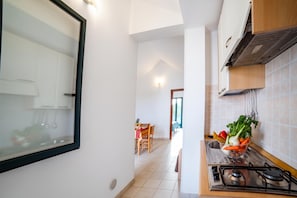 A kitchen with a gas stove, a sink, and a window overlooking a dining area. - Beach in 5 min | Pool Access | n.64, Otranto, Italy (Otranto)