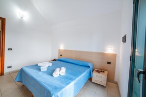 Een hotelkamer met een bed, nachtkastje, telefoon en een 'Welcome' bord.
