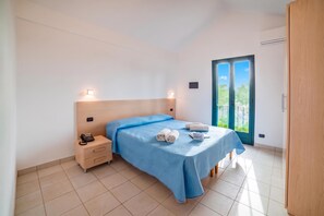 A bedroom with a bed, bedside table, and a view of the outdoors. - Beach in 5 min | Pool Access | n.64, Otranto, Italy (Otranto)
