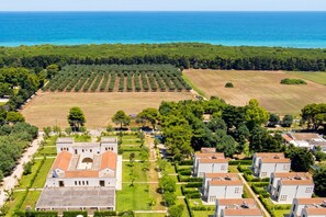A coastal property with a large building, a vineyard, and a view of the sea.