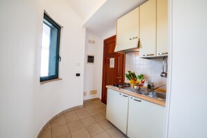 A compact kitchen with white cabinets, a window, and a sink.