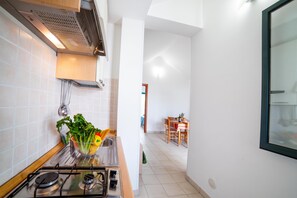 A modern kitchen with a gas stove, a sink, and a countertop with fresh vegetables. - Beach in 5 min | Pool Access | n.58, Otranto, Italy (Otranto)