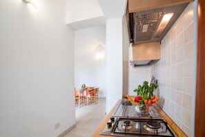 A kitchen with a gas stove, a sink, and a dining area with a table and chairs. - Beach in 5 min | Pool Access | n.56, Otranto, Italy (Otranto)