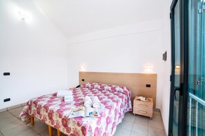 A hotel room with a bed, a nightstand, a drawer, and a window.