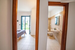 Ein Hotelzimmer mit Bett, einem Badezimmer mit Waschbecken und Toilette sowie einer Tür zu einem Balkon.