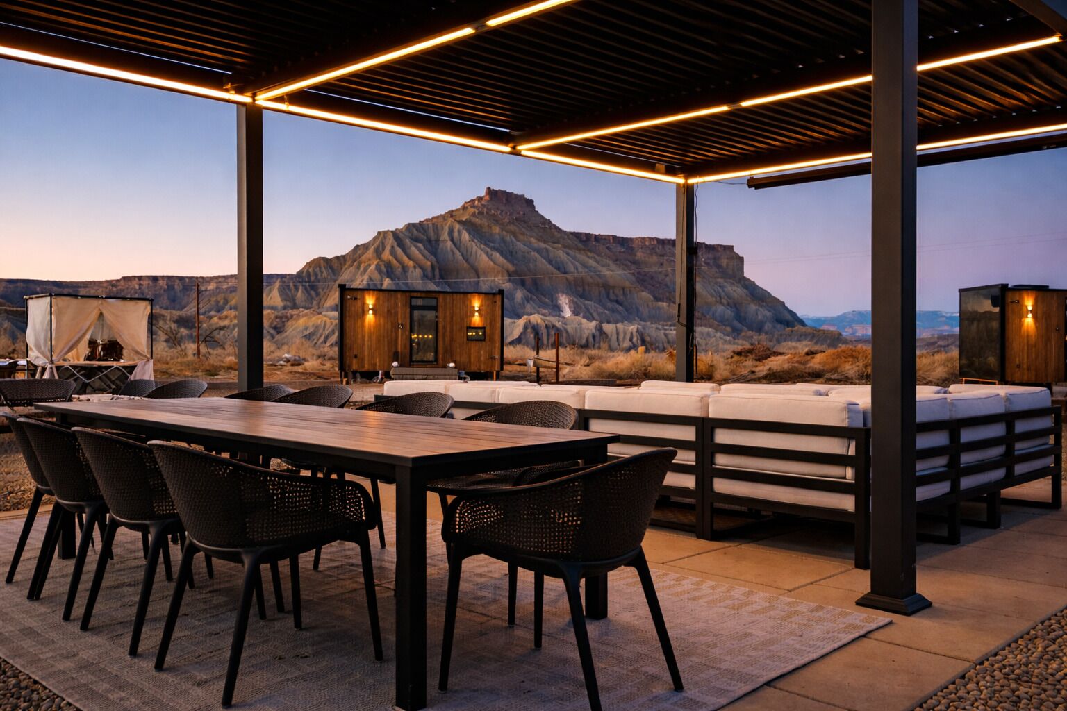 Un patio al aire libre con una mesa y sillas de madera, un sofá y una pequeña estructura de madera con luces.