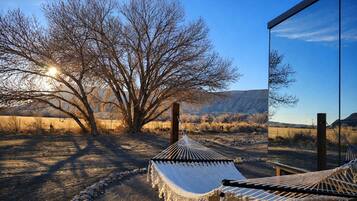 A hammock in a natural setting with a clear view of a mountain range.