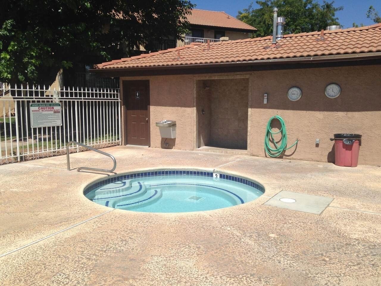 A swimming pool with a tiled edge, a metal ladder, and a hose reel.