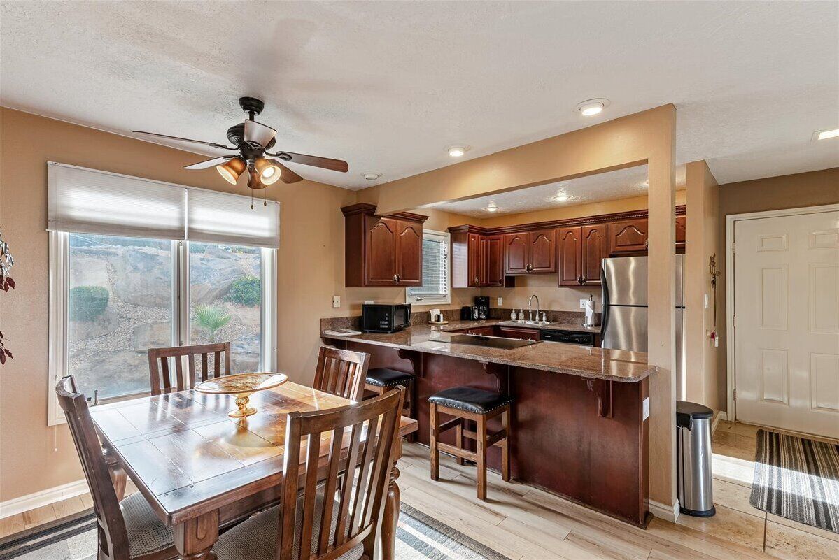 A modern kitchen with a central island, wooden cabinets, and a dining area with chairs.
