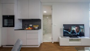 A modern kitchen with white cabinetry, a built-in oven, and a dining area with a TV. - Luxury City Apartment Adialuxe S4, Rijeka, Croatia (Rijeka)