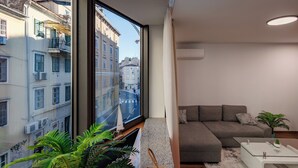 A modern living room with a large window, a gray sofa, a coffee table, and a potted plant. - Luxury City Apartment Adialuxe S4, Rijeka, Croatia (Rijeka)