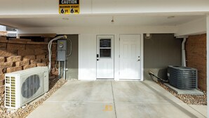 Une entrée d’immeuble avec un panneau d’avertissement, une porte, un appareil de climatisation et un mur en briques.