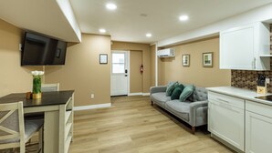 Un appartement moderne comprenant un coin repas, un canapé, une cuisine et un téléviseur à écran plat fixé au mur.