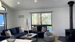 A modern living room with two sofas, a coffee table, a lamp, a bean bag, and a fireplace.
