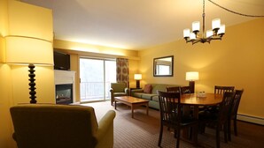 Une chambre d’hôtel équipée d’une table à manger, de chaises, d’un canapé, d’une cheminée et d’un téléviseur.