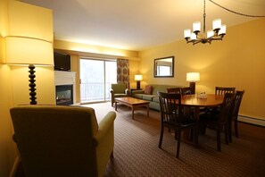 Ein Hotelzimmer mit Esstisch, Stühlen, einer Couch, einem Kamin und einem Fernseher.