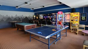 Un espace de loisirs équipé d’une table de billard, d’une table de ping-pong et de divers jeux d’arcade.