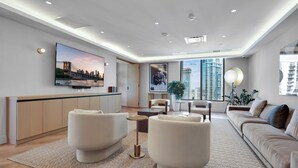 A modern living room with a flat-screen TV, a sofa, a coffee table, and a large window with a view of high-rise buildings. - 501 First Luxury Ocean View from Balcony Rooftop Pool & GYM 2110 (Miami)