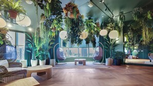 A room with a wooden floor, round tables, hanging plants, and wicker furniture. - 501 First Luxury Ocean View from Balcony Rooftop Pool & GYM 2110 (Miami)