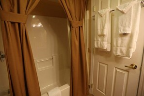 A bathroom with a shower curtain, a bathtub, and a door with towels hanging on it. - Wonderful 2-Bedroom Condo Located at Pollard Brook (Lincoln)