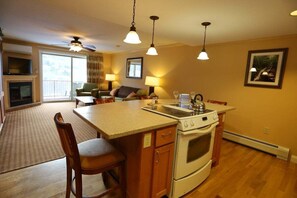 A kitchen with a central island, a stove, and a dining area with chairs. - Wonderful 2-Bedroom Condo Located at Pollard Brook (Lincoln)