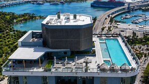 A modern hotel with a rooftop pool, a large circular structure, and a view of the marina and city skyline. - 501 First Luxury 1 BR + Den & 2 Baths Rooftop Pool & GYM 502 (Miami)