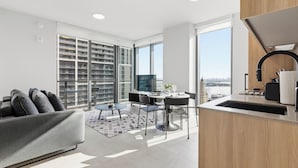 Un appartement moderne doté d’un coin repas, d’une cuisine et de grandes fenêtres offrant une vue sur la ville.
