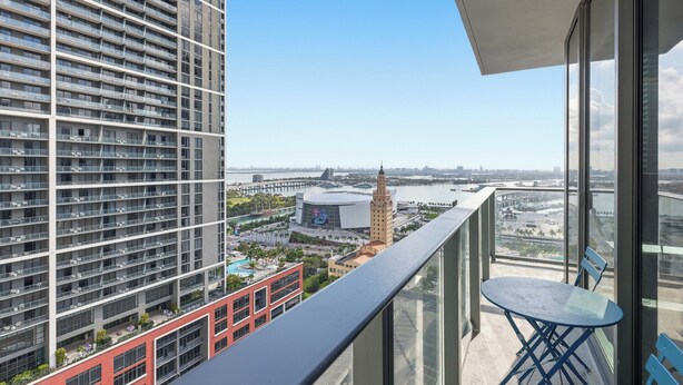 Un balcon offrant une vue dégagée sur un bâtiment moderne, une tour distante et une étendue d’eau.