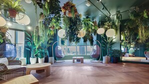 Une pièce dotée d’un plancher en bois, de meubles en osier, de plantes suspendues et de grandes fenêtres.