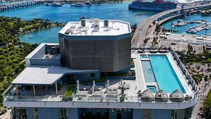 Un hôtel moderne doté d’une piscine sur le toit, d’une vaste structure circulaire et offrant une vue sur le port de plaisance et le panorama urbain.