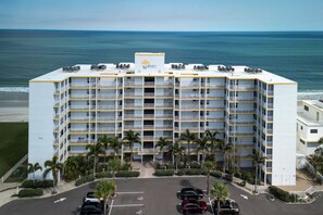 Un hôtel à plusieurs étages, doté de balcons, d’un parking et offrant une vue sur l’océan.