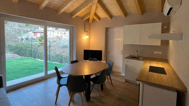 Uma cozinha moderna com teto de madeira, uma mesa de jantar com cadeiras, forno embutido e uma janela grande com vista para o exterior.