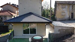 Uma casa com telhado de telhas, hidromassagem e um alpendre coberto.