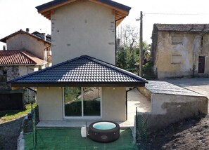 Ein Haus mit einem Ziegeldach, einem Whirlpool und einer überdachten Terrasse.