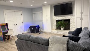 A living room with a sofa, a flat-screen TV, a fireplace, cabinets, and a gaming console. - Sunset cruiser close to Redington Beach (Seminole)