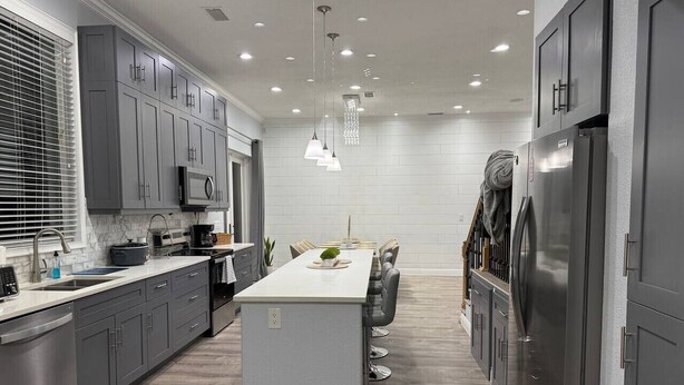 A modern kitchen with grey cabinets, a central island, stainless steel appliances, and pendant lighting. - Sunset cruiser close to Redington Beach (Seminole)